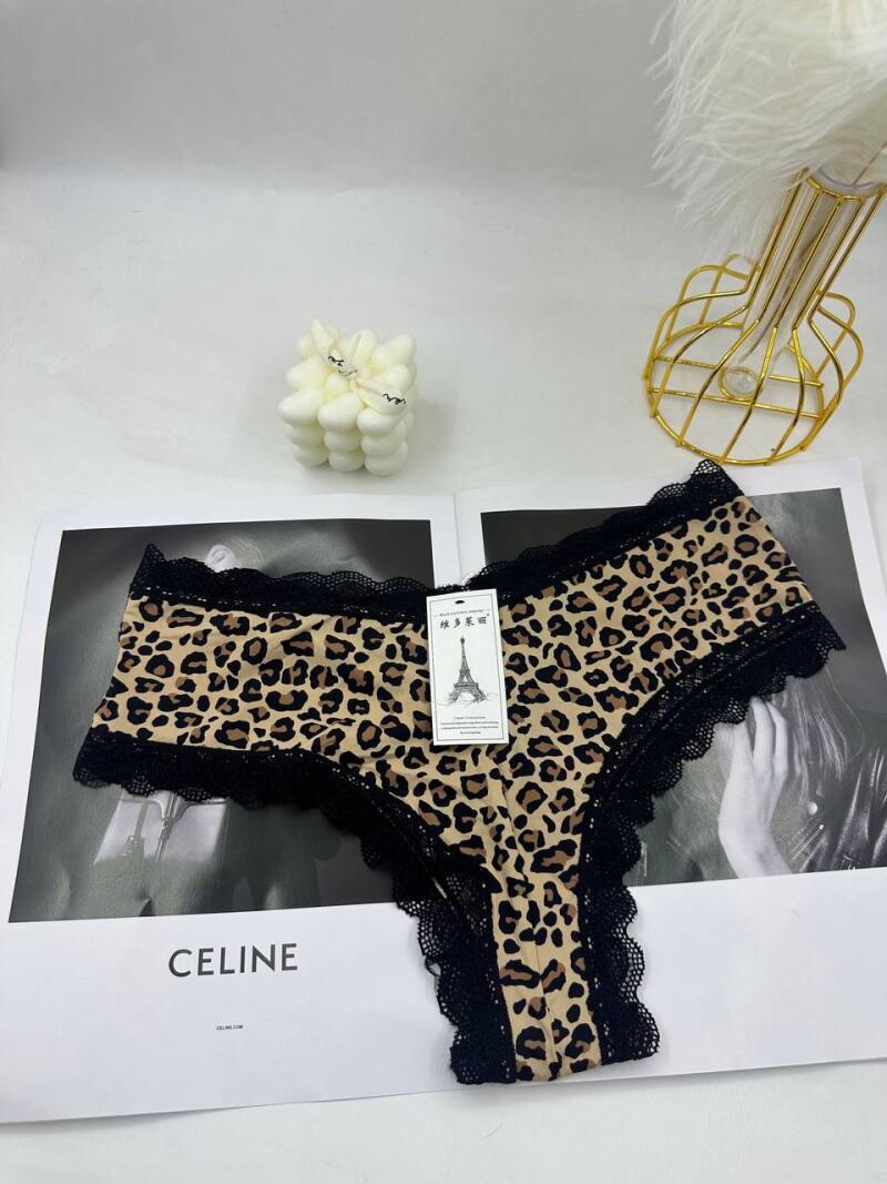 The photo displays leopard-print underwear with black lace trim, placed on a magazine featuring the word "CELINE". Beside it are a candle, and a feather decoration in a gold wire stand.