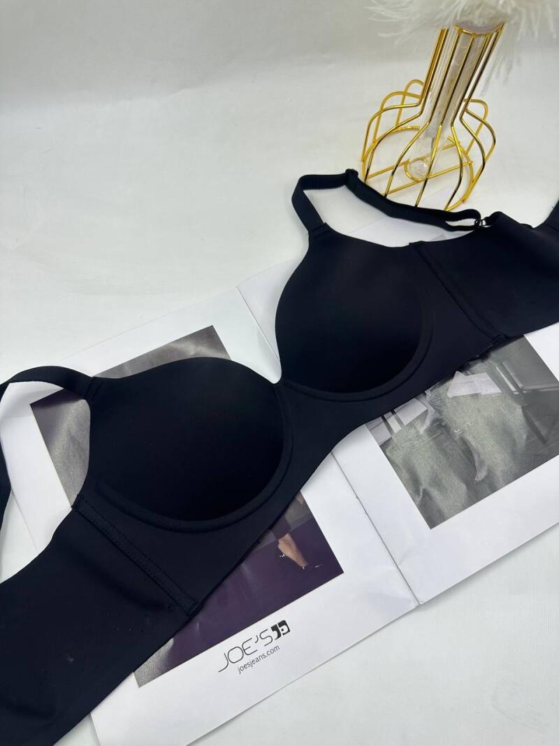 A black bra is placed on top of a magazine featuring the 'Joe's' logo and the website 'joejeans.com'. A decorative golden vase is in the background.