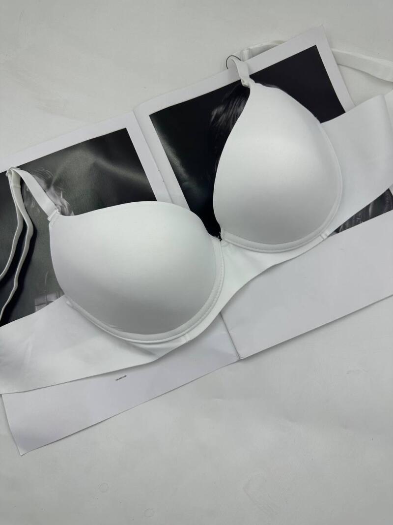 A white bra with straps lies on top of a magazine with a black and white image.