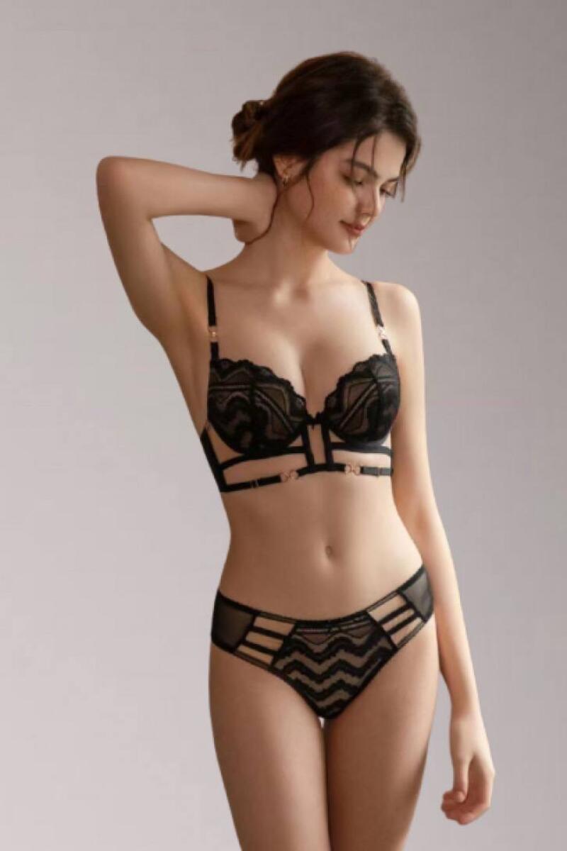A woman is posing in a black lace bra and underwear set.