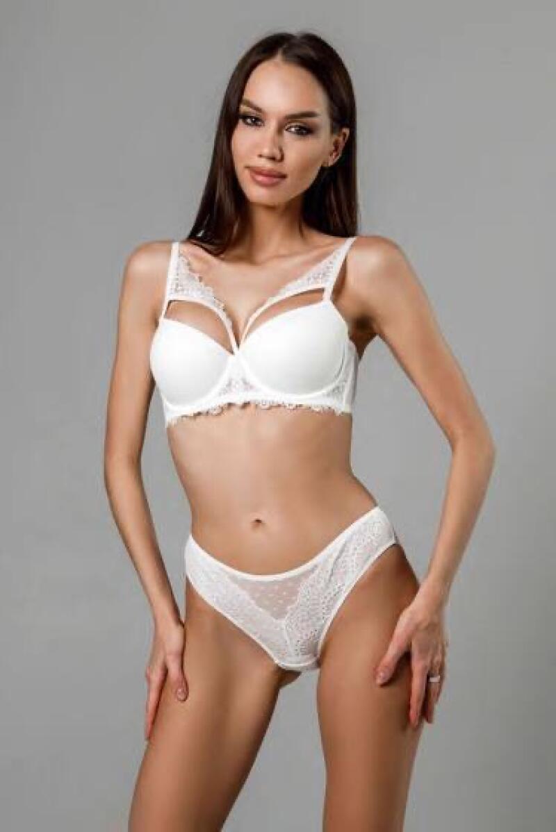 A woman in a white lingerie set is posing against a gray background.