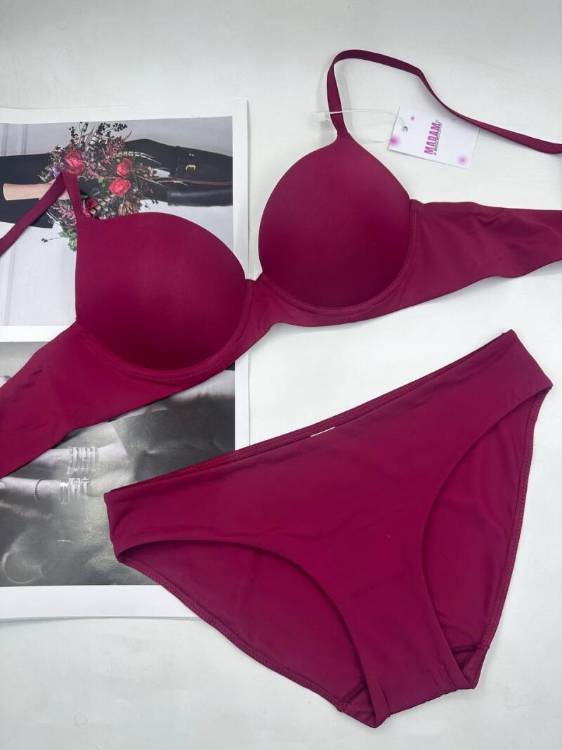 A maroon bra and underwear set are displayed next to a framed photo on a white surface. The bra is a push-up style with a tag that reads "Madam."