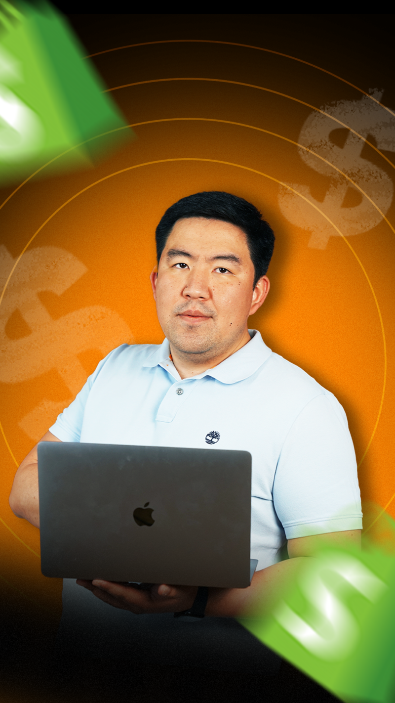 A man holds a laptop with an Apple logo, wearing a light blue Timberland polo shirt against an orange background with dollar sign graphics.