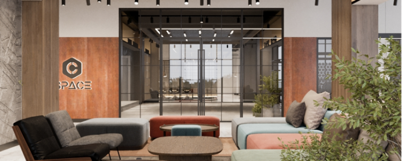 The image shows a modern office lounge area with comfortable seating, tables, and a view into another well-lit office space through glass doors. The wall features the 'C Space' logo.