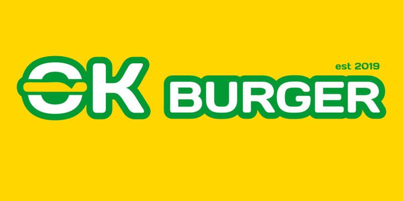 На изображении представлен логотип "OK Burger" зеленым и белым цветом на ярко-желтом фоне, с надписью "est 2019", расположенной над "Burger". Буква 'O' в 'OK' пересечена горизонтальной зеленой линией.