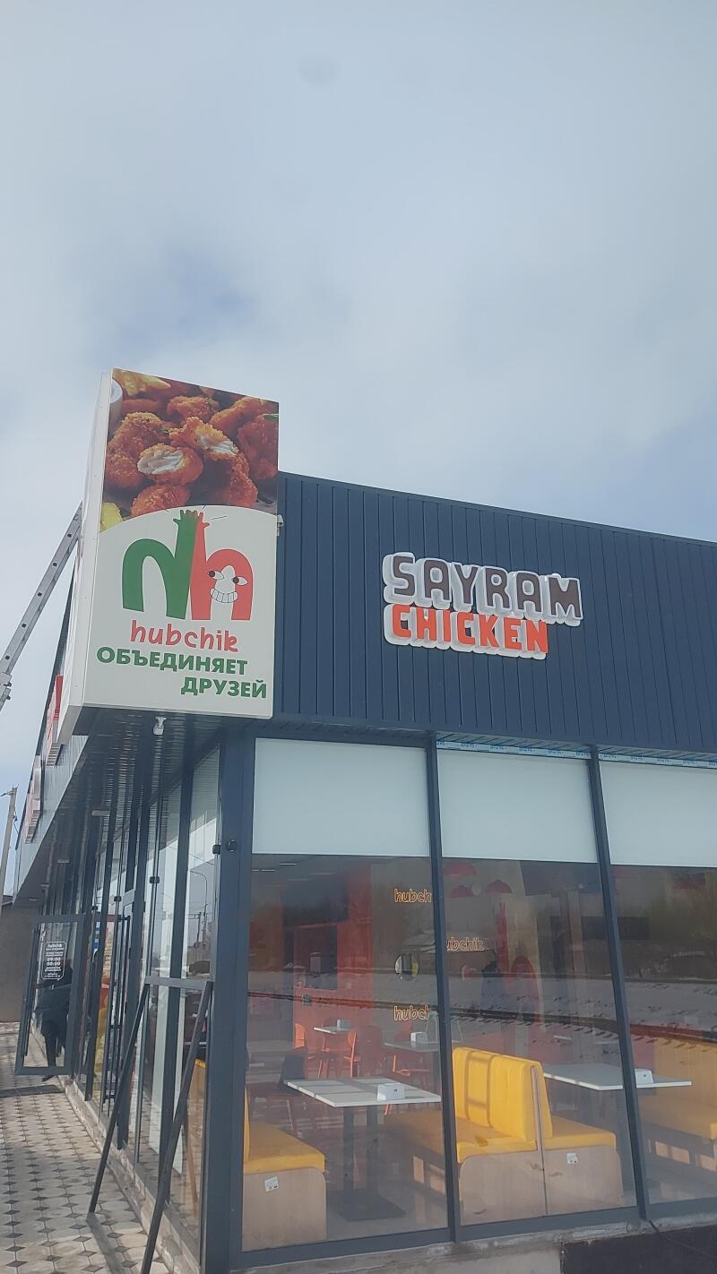 The exterior of a restaurant with a sign for "Sayram Chicken" is visible, along with a logo for "hubchik объединяет друзей" featuring an image of fried chicken.