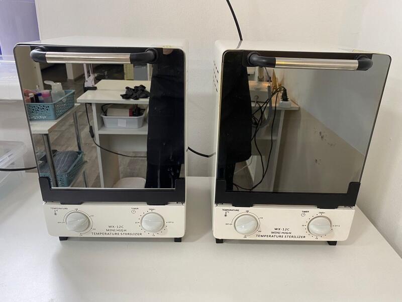 Two white WX-12C Mini High Temperature Sterilizers are displayed side by side on a table.