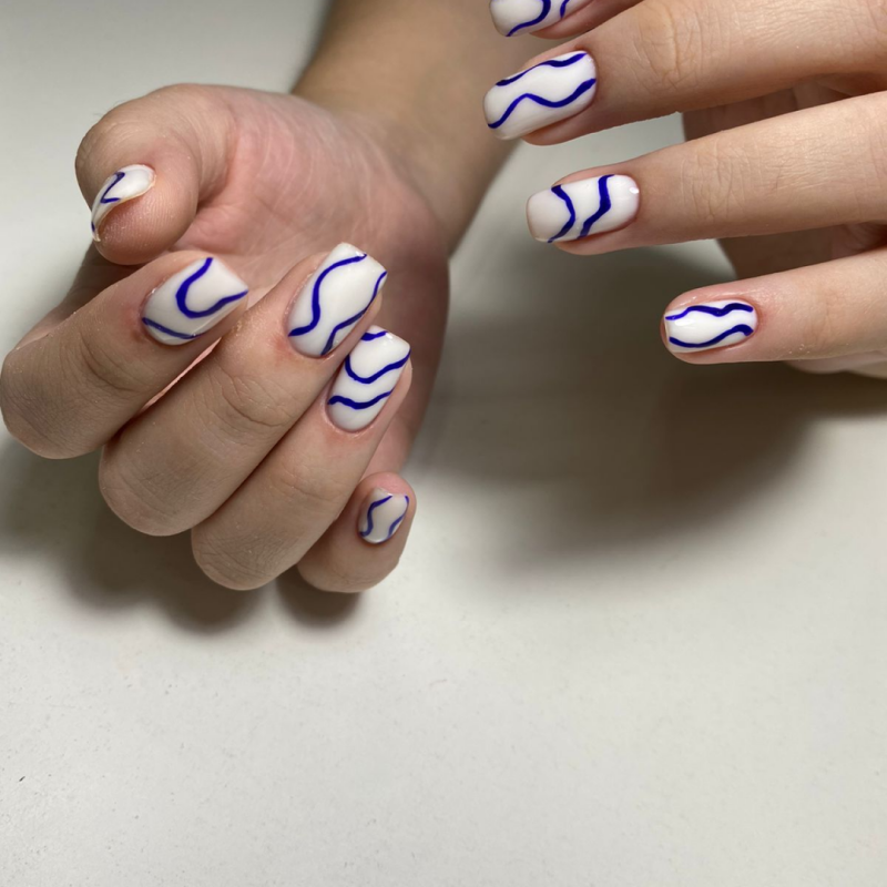 A close-up shot shows hands with white nails adorned with blue wavy lines.