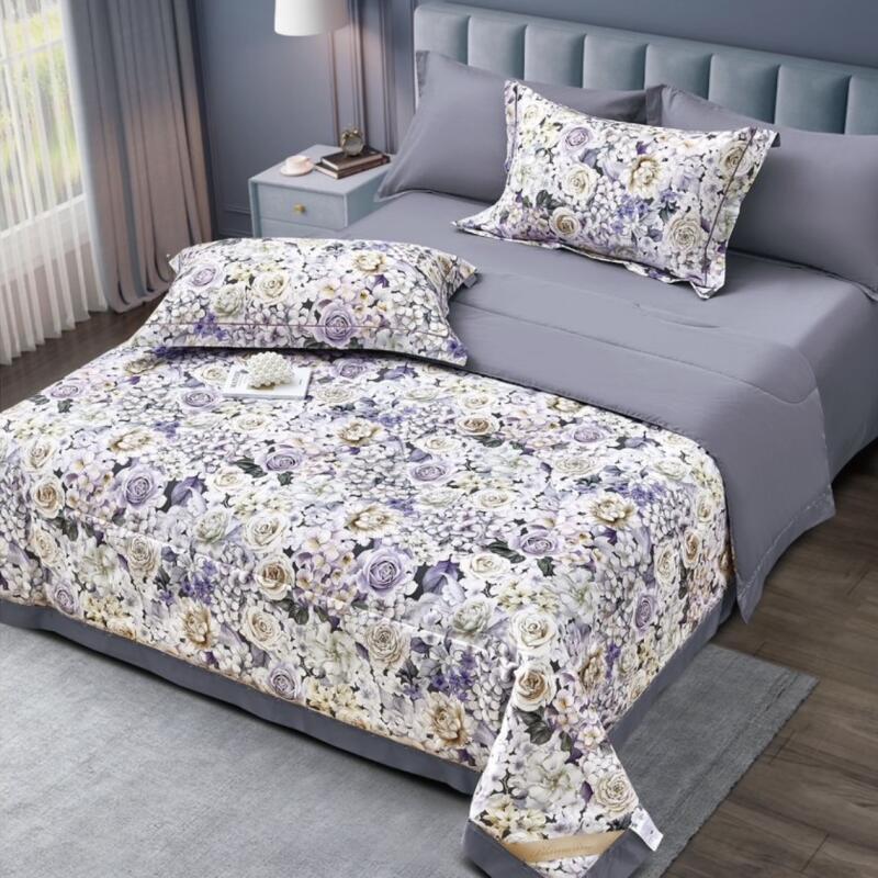 A bedroom features a neatly made bed with gray sheets and floral-patterned pillows and comforter, alongside a gray bedside table.