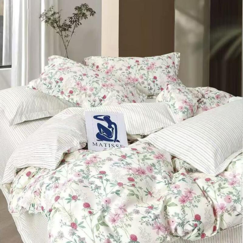 The image shows a bed with white bedding with floral and striped patterns; a card with a blue abstract figure and the text "MATISSE" is placed on the bed.