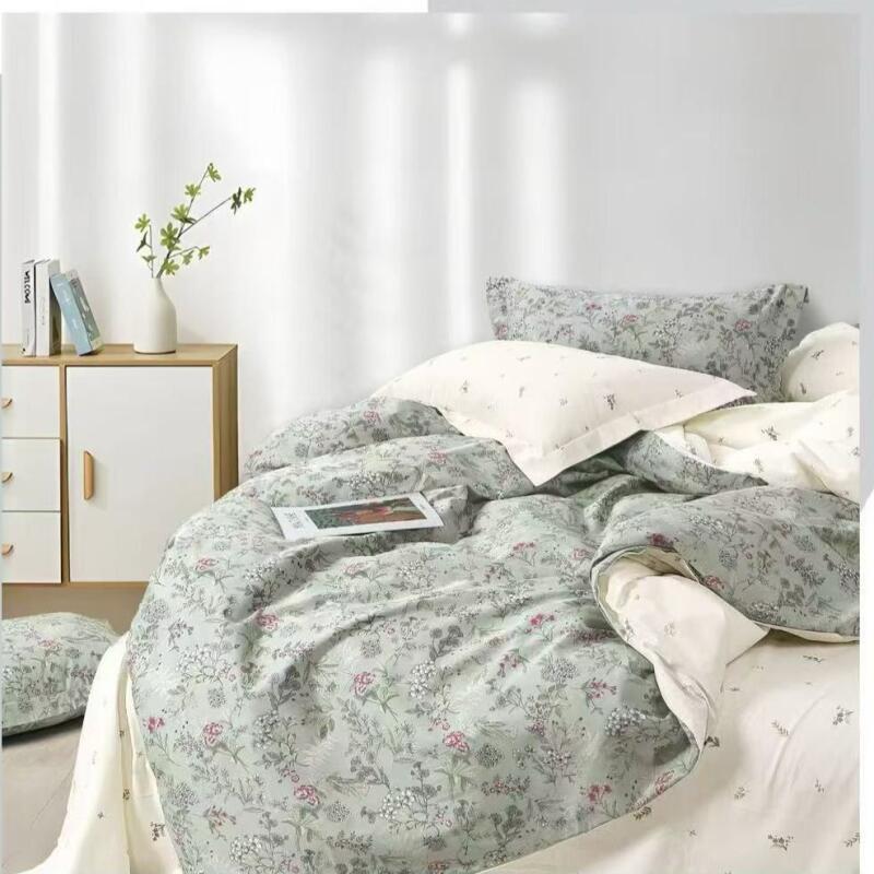 A neatly made bed features floral-patterned bedding, complemented by a white nightstand with books and a vase of greenery.
