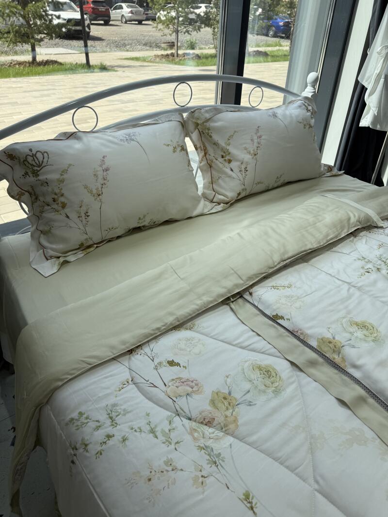 A bed is made with pillows and a duvet cover with a floral design.