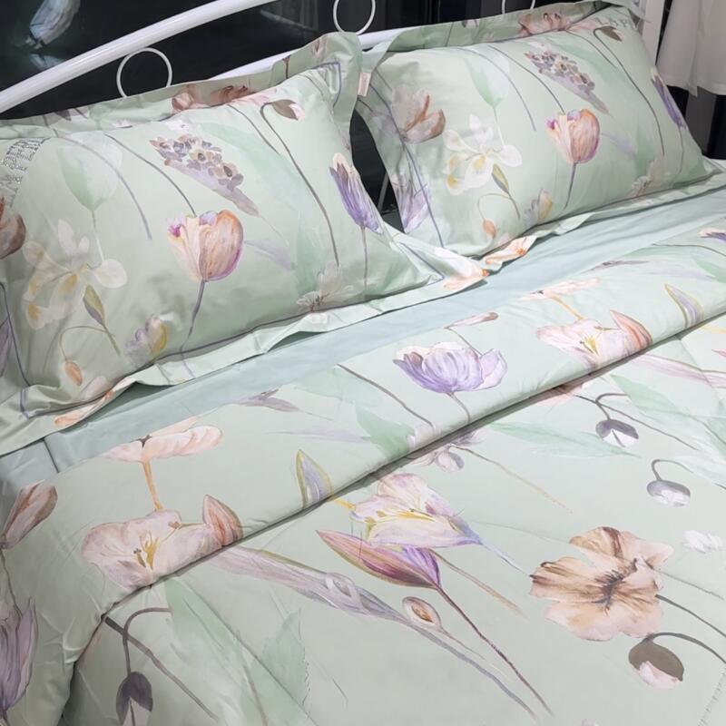 The image shows a bed with floral-patterned bedding in pastel colors, including two pillows with the same floral design.