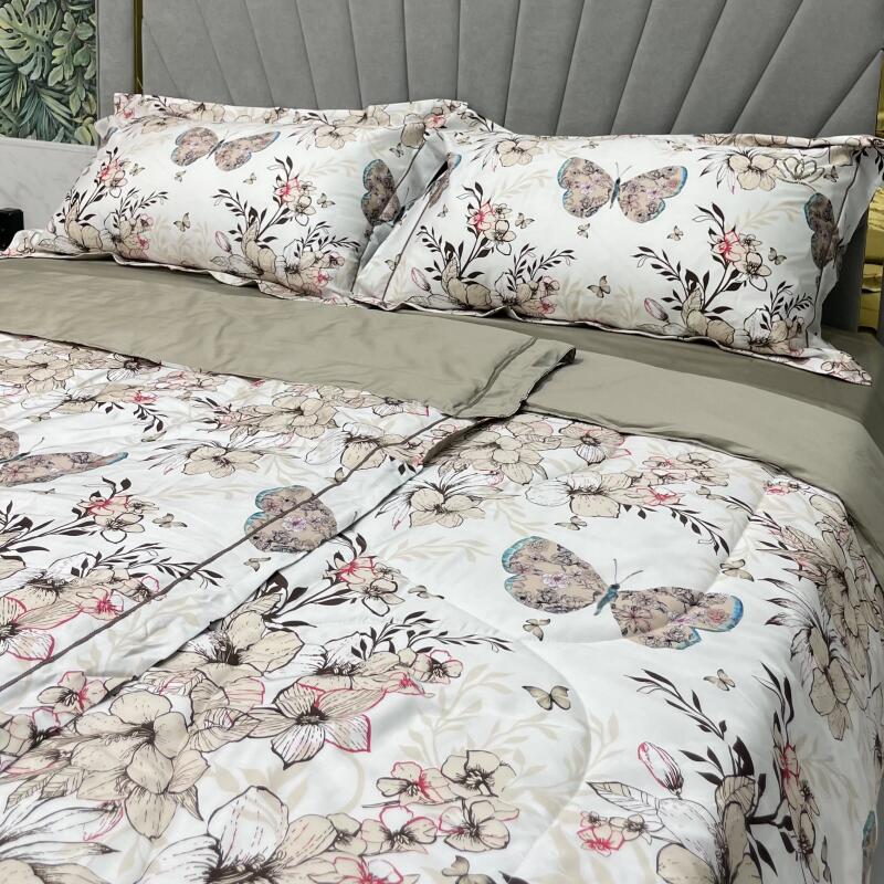 The image shows a bed with a floral and butterfly-patterned comforter and matching pillowcases. The bedding has a predominantly white background with floral and butterfly designs in shades of brown, pink, and blue.