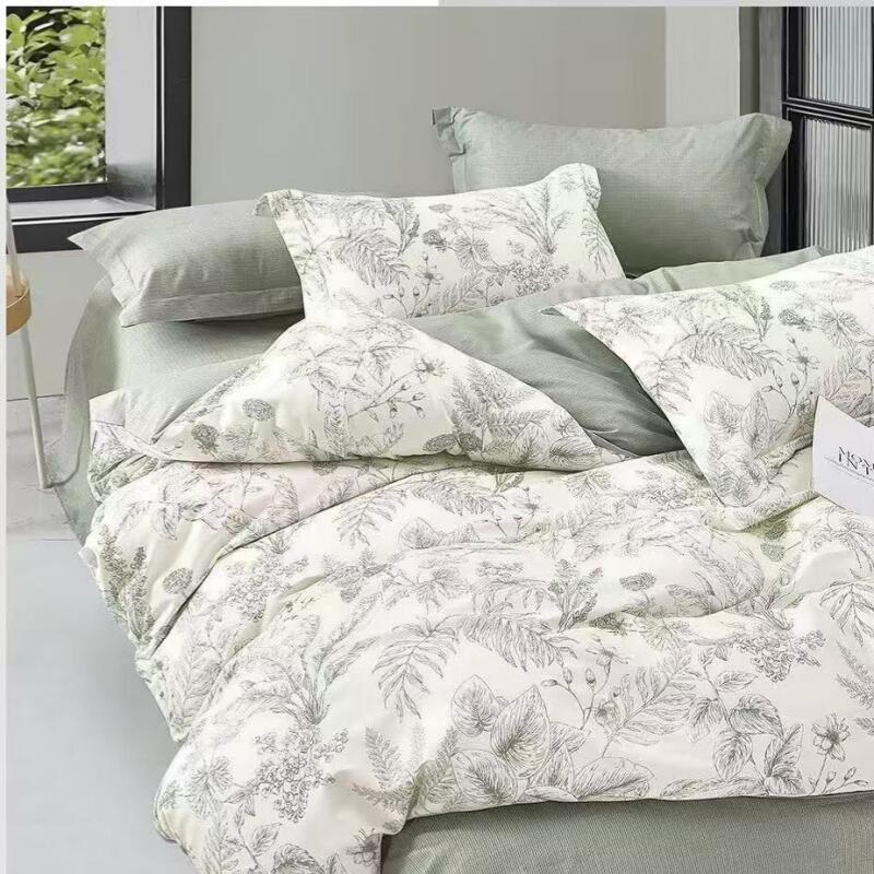 A bed is covered in light green sheets and pillows, with a white duvet cover and pillowcases featuring a grey floral pattern.