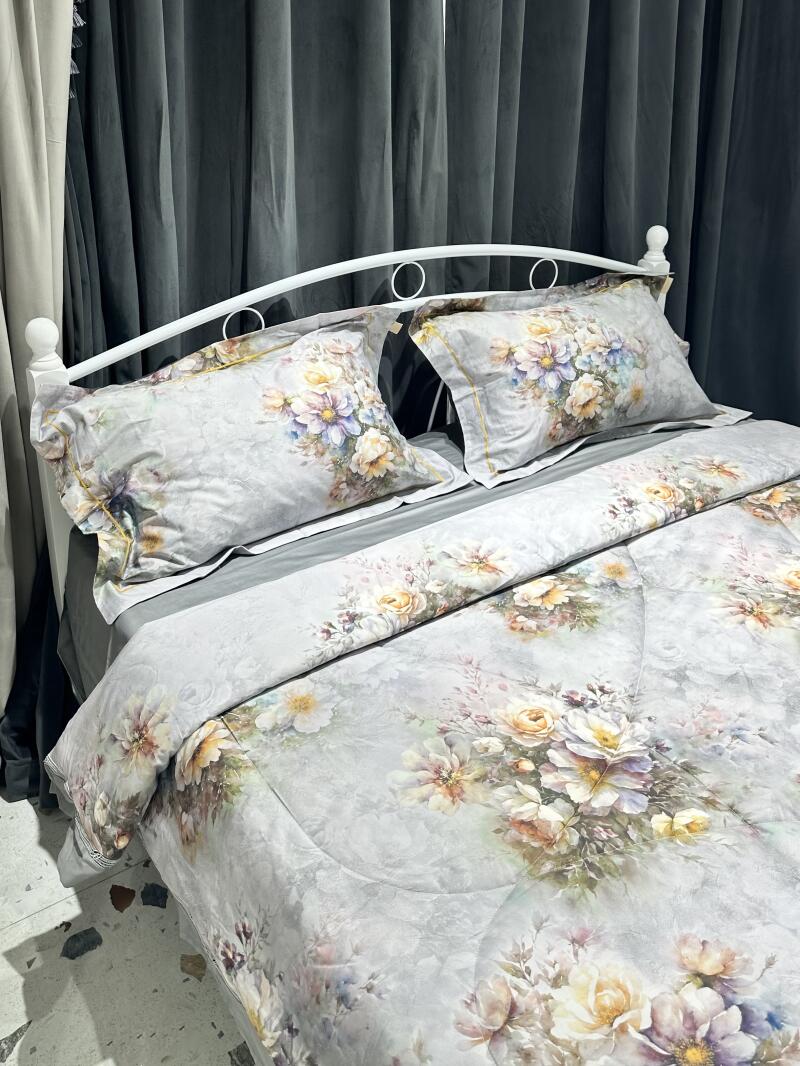 A bed with white frame is covered in a floral patterned comforter and pillows, set against dark curtains.