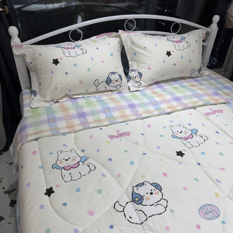 The bed is made with white sheets and pillowcases decorated with cartoon puppies and colorful dots, covered with a plaid top sheet.