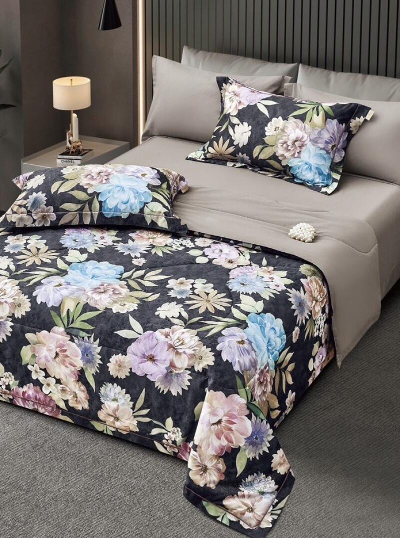 The image shows a made bed with floral patterned comforter and pillow cases, set against a neutral gray background with a bedside table and lamp.