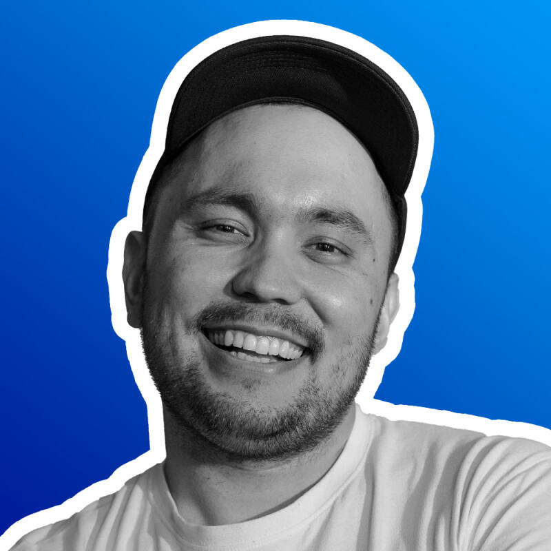 A grayscale portrait of a smiling man wearing a black cap and a white t-shirt, set against a blue background with a white outline.