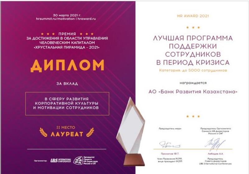 The image shows two award certificates, one for the 'Crystal Pyramid - 2021' award for achievements in human capital management, and the other for 'Best Employee Support Program in Times of Crisis,' awarded to 'Bank Development of Kazakhstan,' alongside a crystal award on a wooden base.