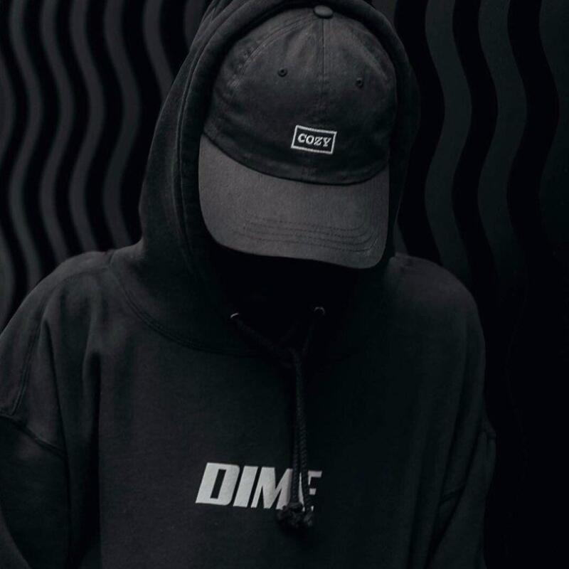 A person wearing a black hoodie with the word "DIME" on it and a black cap with the word "COZY" on it is set against a black wavy background.