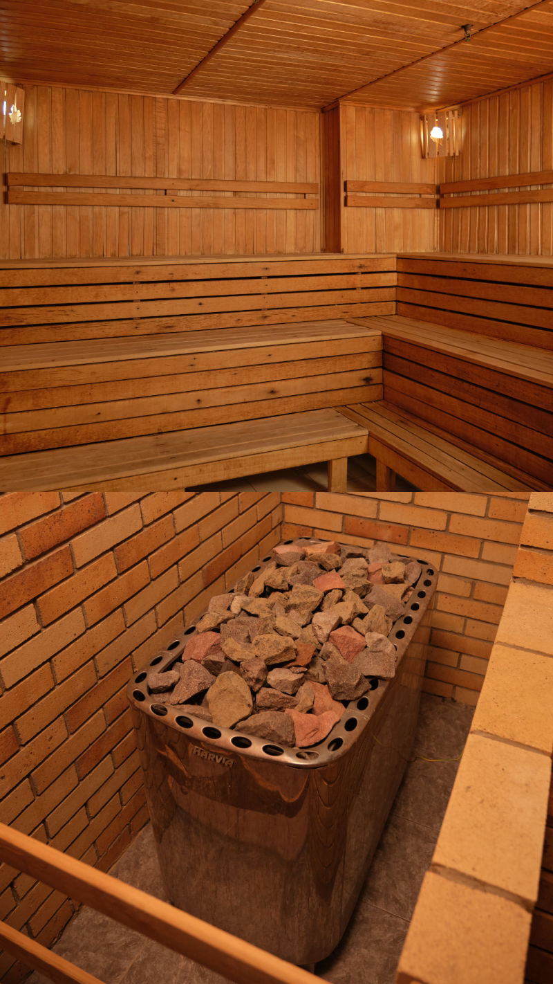 The image shows the interior of a sauna, featuring wooden benches and paneling along the walls and ceiling, and a rock-filled heater with the brand name "HARVIA" visible on its side, set against a brick wall.