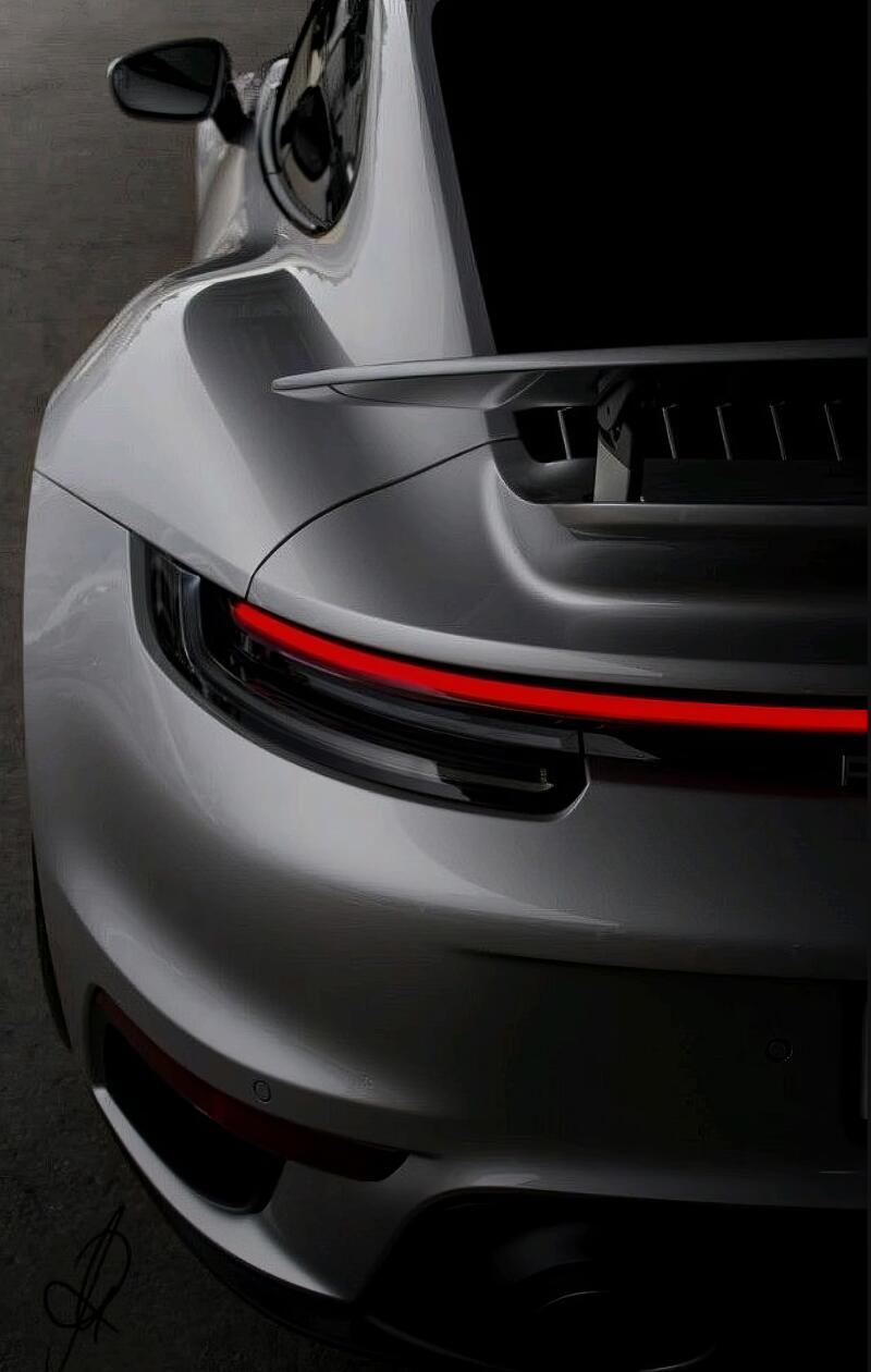 The rear view of a silver Porsche reveals a sleek design with a red taillight strip and a spoiler.