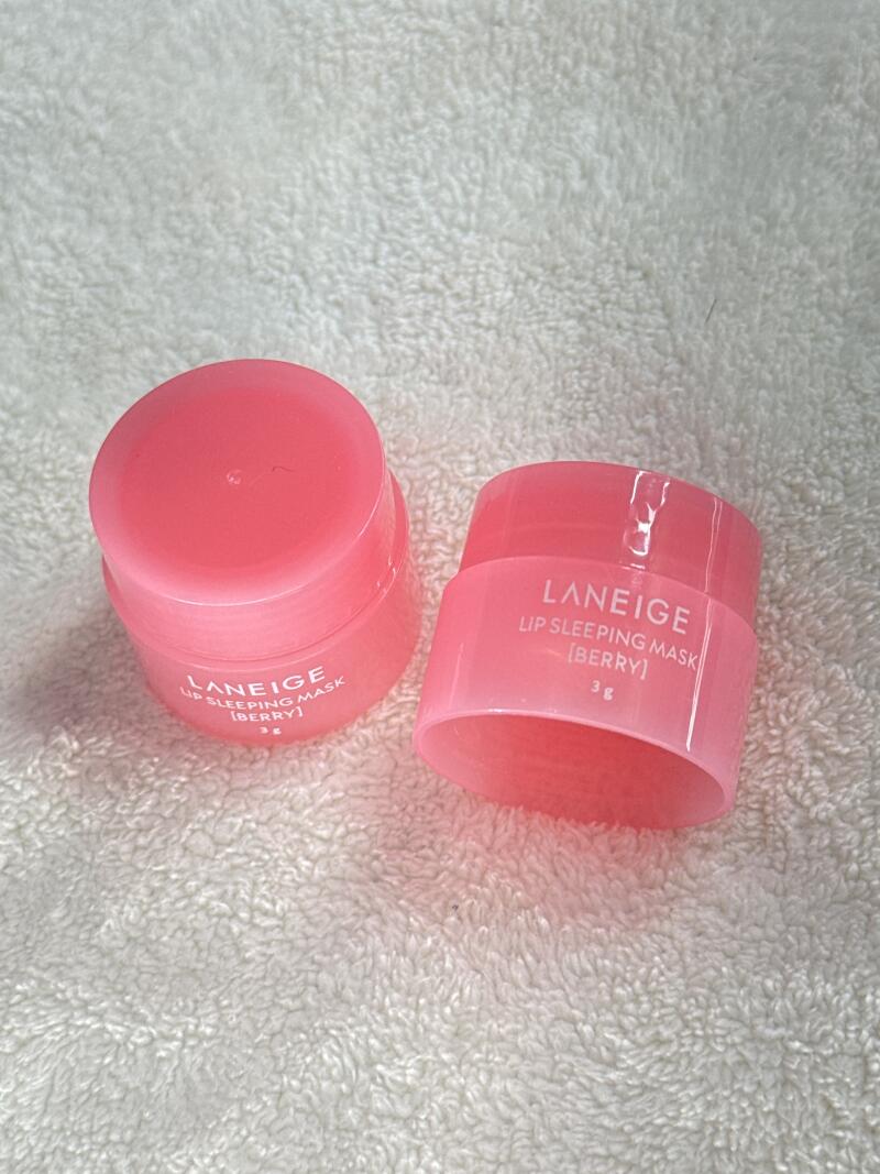 Two small, pink containers of Laneige Lip Sleeping Mask [Berry] 3g are on a white, textured surface.