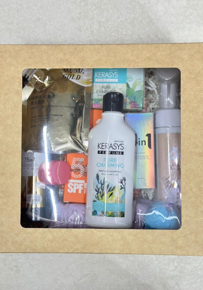 A box filled with beauty products, including a gold face mask, perfume shampoo by Kerasys with the label 'Pure Charming', SPF, and other skincare items.