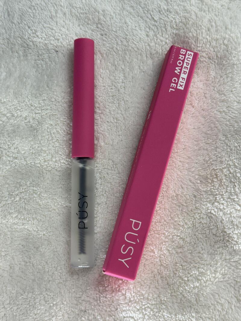 A tube of PUSY super fix brow gel with a pink handle is next to the pink box.
