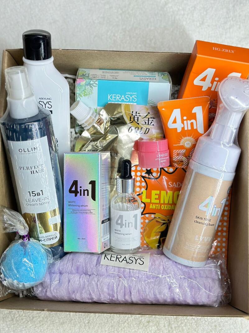 A cardboard box is filled with various skincare and haircare products, including brands like Aekyung, Ollin, Kerasys, and a product line labeled '4in1' offering whitening serum and skin tone cleansing foam, alongside items like leave-in cream spray, lip sleeping mask, and an anti-oxidation lemon-themed product.