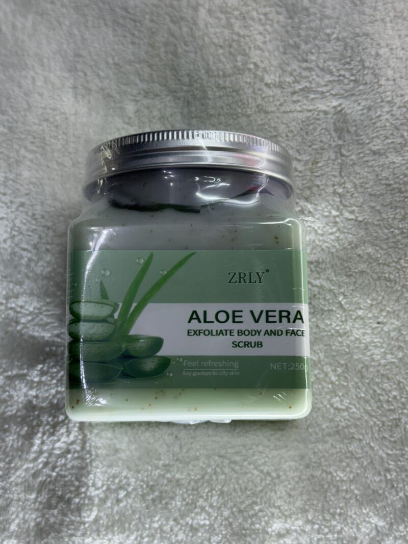 A jar of ZRly Aloe Vera Exfoliate Body and Face Scrub with a silver lid is displayed, with the text 'Feel refreshing, Say goodbye to oily skin' and 'NET: 250' printed on the label.