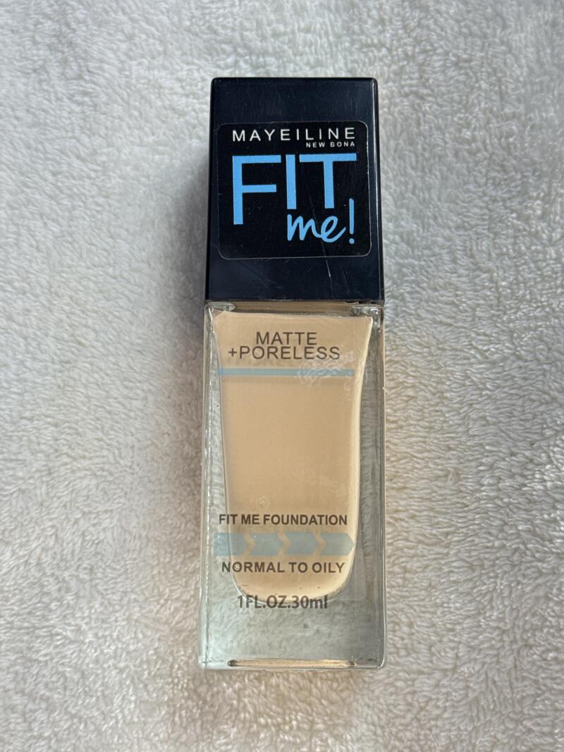 A bottle of Maybelline Fit Me foundation with a black cap and clear bottle, labeled 'MATTE + PORELESS, FIT ME FOUNDATION, NORMAL TO OILY, 1FL.OZ.30ml'.