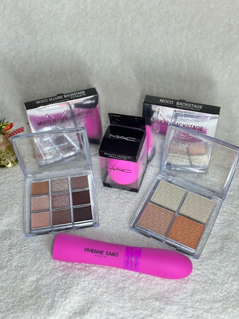 The photo features a variety of makeup products including two MOCO Allure Backstage eye palettes, two MOCO Backstage glow face palettes, a MAC beauty makeup sponge, and a pink Vivienne Sabó mascara.