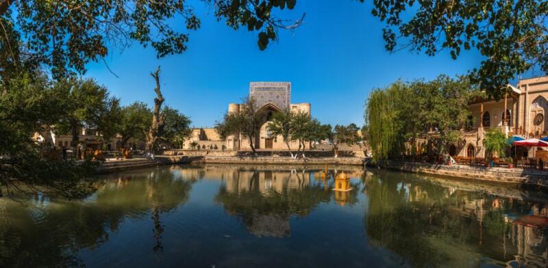 A scenic view of a pond reflecting a building with intricate tile work under a clear blue sky.