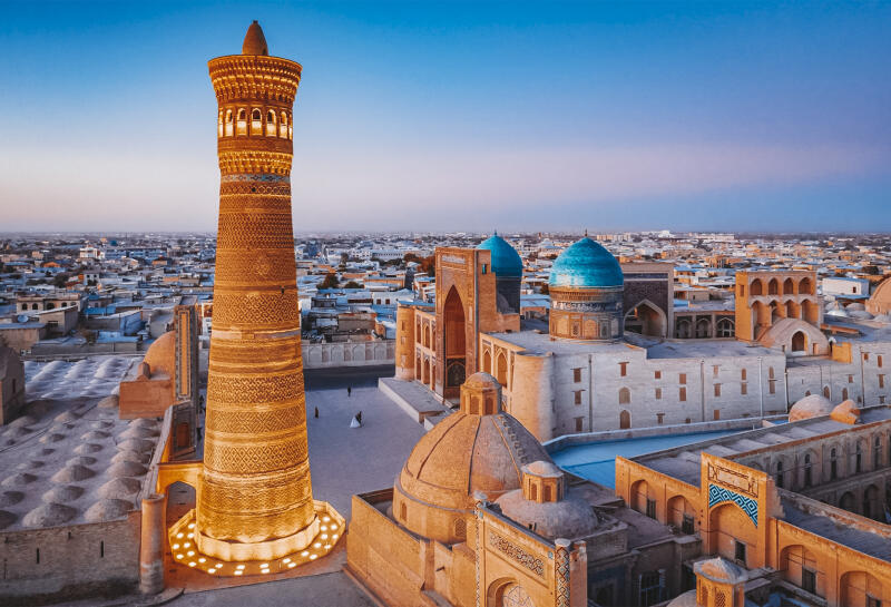 An aerial shot of the Kalon Minaret and other buildings in Bukhara, Uzbekistan, taken at dusk.