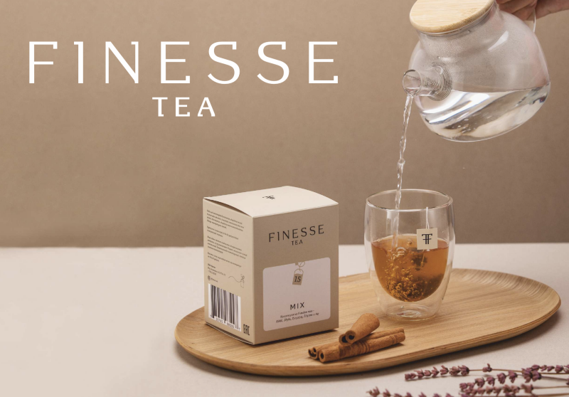The image shows a box of Finesse Tea next to a glass of tea being poured from a glass teapot, along with cinnamon sticks and lavender sprigs on a wooden tray, with the text "FINESSE TEA" prominently displayed.