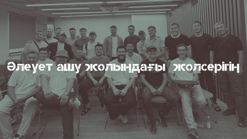 A grayscale, eye-level group shot of about twenty men sitting in chairs, overlaid with the text "Әлеует ашу жолындағы жолсерігің!"