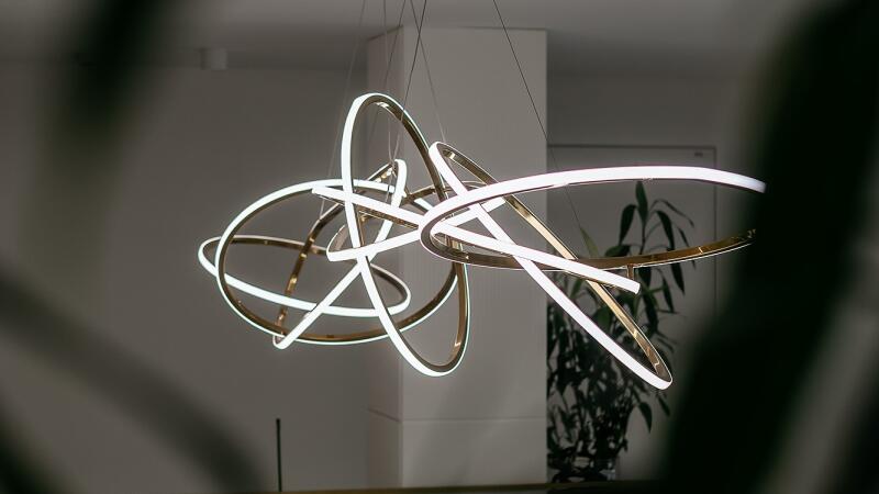 A modern chandelier with intersecting gold rings and white lights hangs from the ceiling.