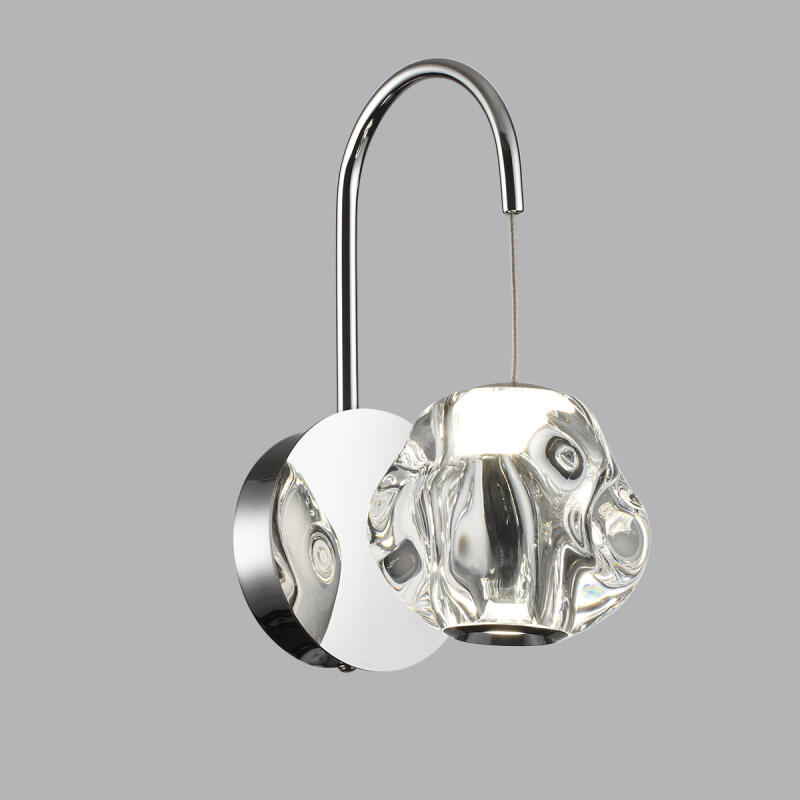 A wall lamp features a shiny, chrome-finished curved arm connected to a circular base, with a clear, textured glass shade hanging from a thin wire.