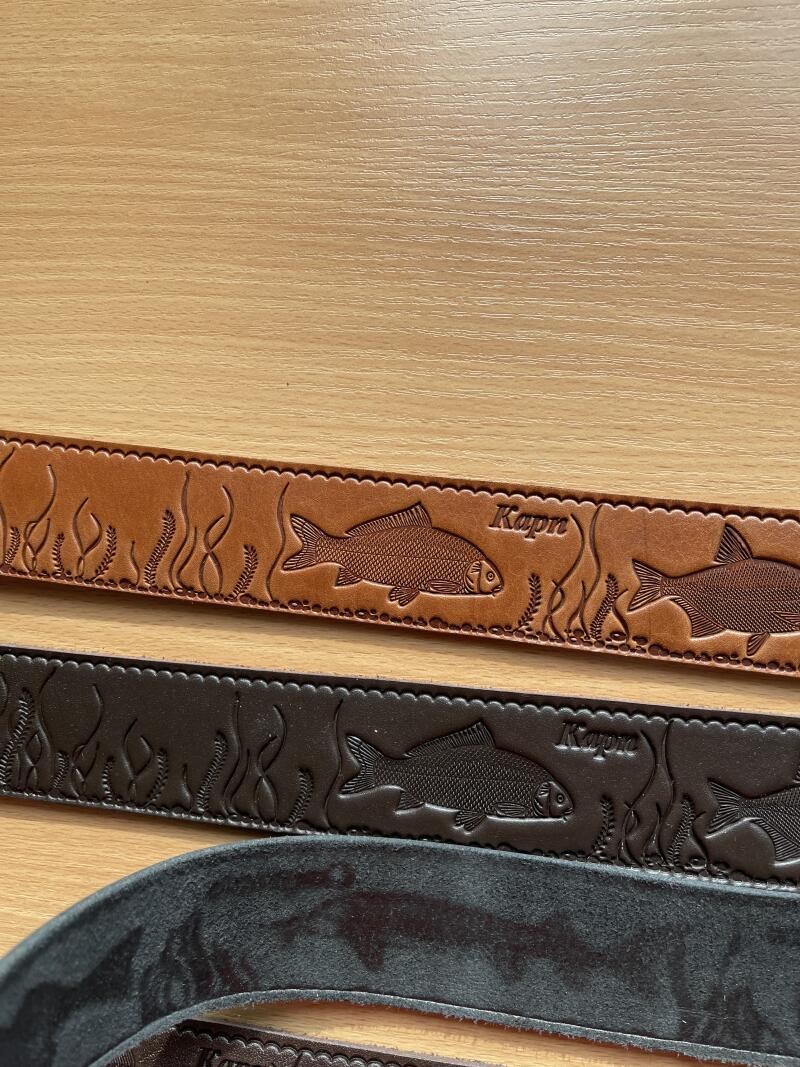 The image shows three leather belts with embossed designs of fish and aquatic plants, along with the word "Kapre". The belts are in different shades of brown.