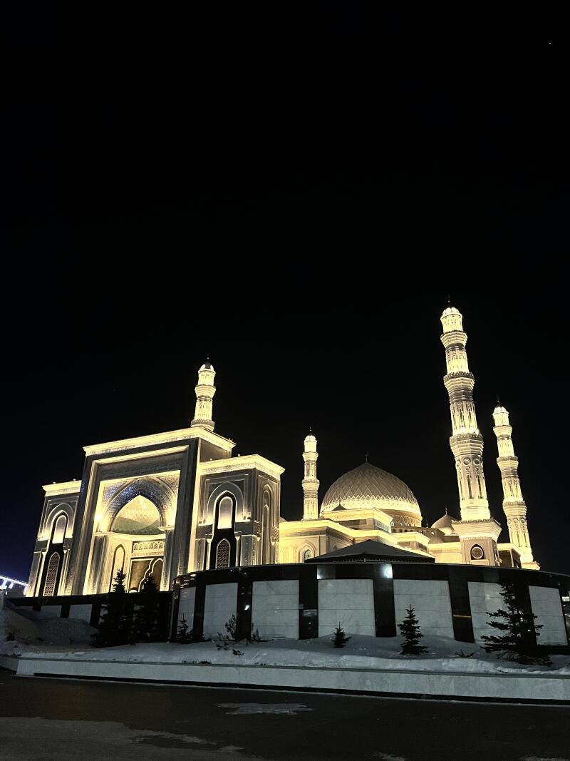 A brightly lit mosque is pictured at night with a dark sky above.