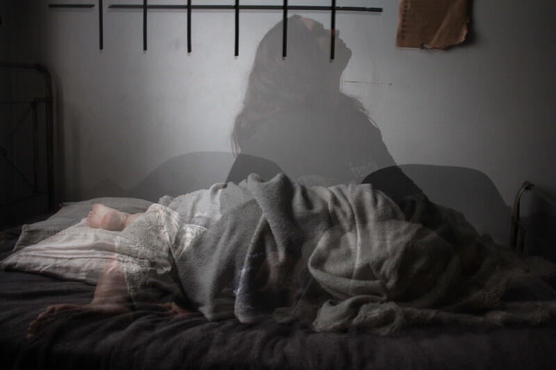 The image shows a person lying in bed covered with a blanket, with an overlaid translucent image of a person sitting up and looking up.
