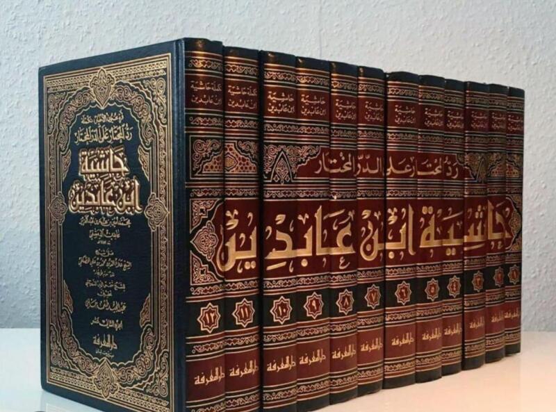 The image shows a collection of books with ornate gold lettering and designs on their spines, including the text 'حاشية ابن عابدين' and 'رد المحتار على الدر المختار'. The books appear to be volumes of a classical Islamic text, with numbers indicating the volume number on the spine.
