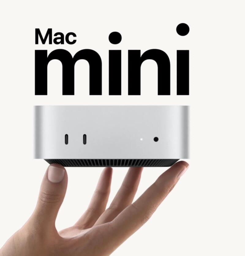 На изображении рука держит серебристый компьютер Mac Mini под черным текстом "Mac mini".
