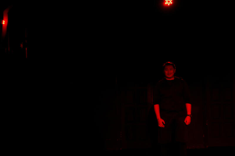 Человек стоит в темном пространстве, освещенном красным светом.