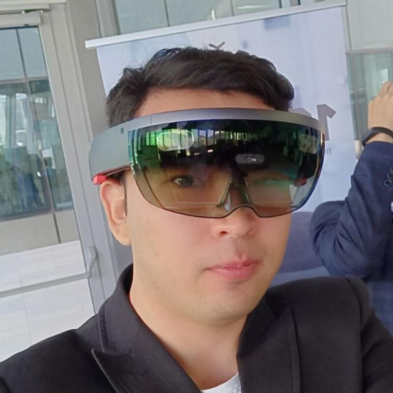 A person is wearing augmented reality glasses and a black suit jacket.