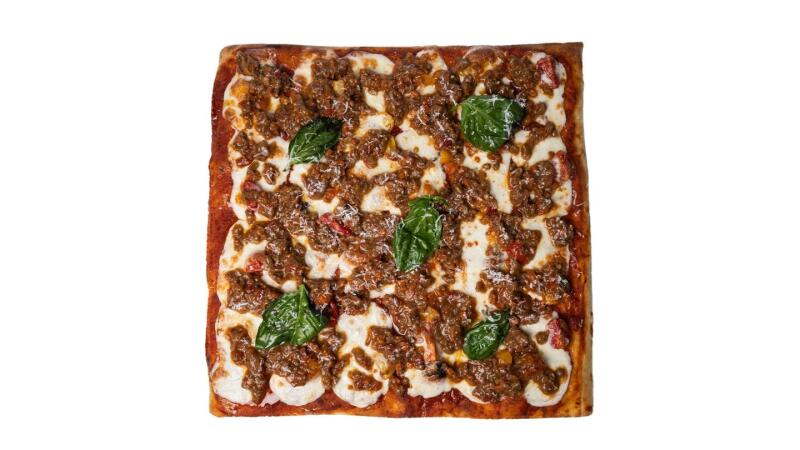 Квадратная пицца с мясным соусом, сыром моцарелла и листьями базилика на белом фоне.