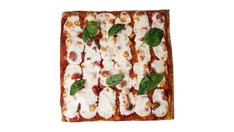 Квадратная пицца с томатным соусом, моцареллой, помидорами и листьями базилика на белом фоне.