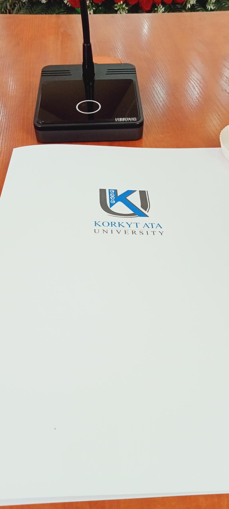 The image shows a black Vissonic microphone next to a white sheet of paper with the KORKYT ATA UNIVERSITY logo in blue and black.